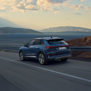 Audi Q4 e-tron kör på en landsväg, sedd snett bakifrån.